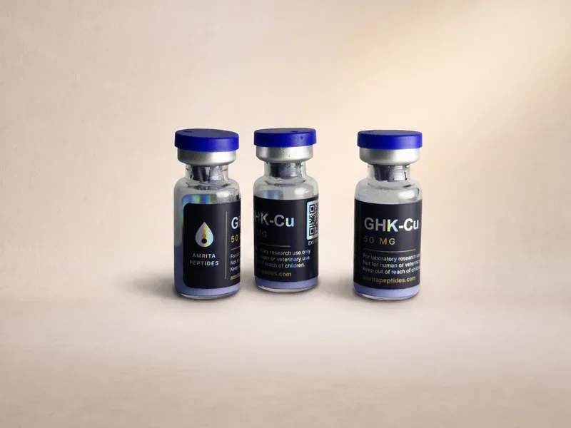 Amrita Peptides labeled GHK-Cu 50 mg copper peptide vials, three upright with blue caps on a beige backdrop